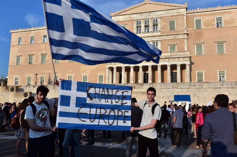 Protesters hold a greek flag with ' change Europe' slogan on it in front of the Greek parliament in Athens [Louisa Gouliamaki]